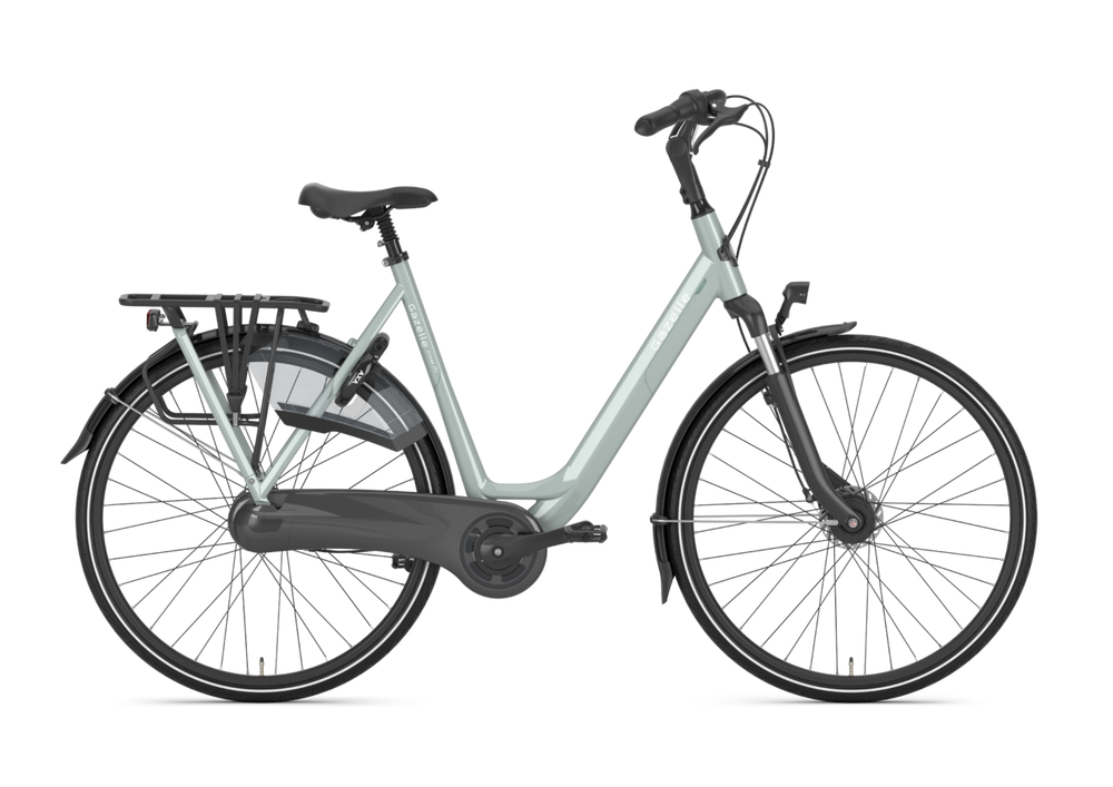Billede af Gazelle Orange C7+ cykel til damer i farven Light Olive, der står på en vej med grønne omgivelser.