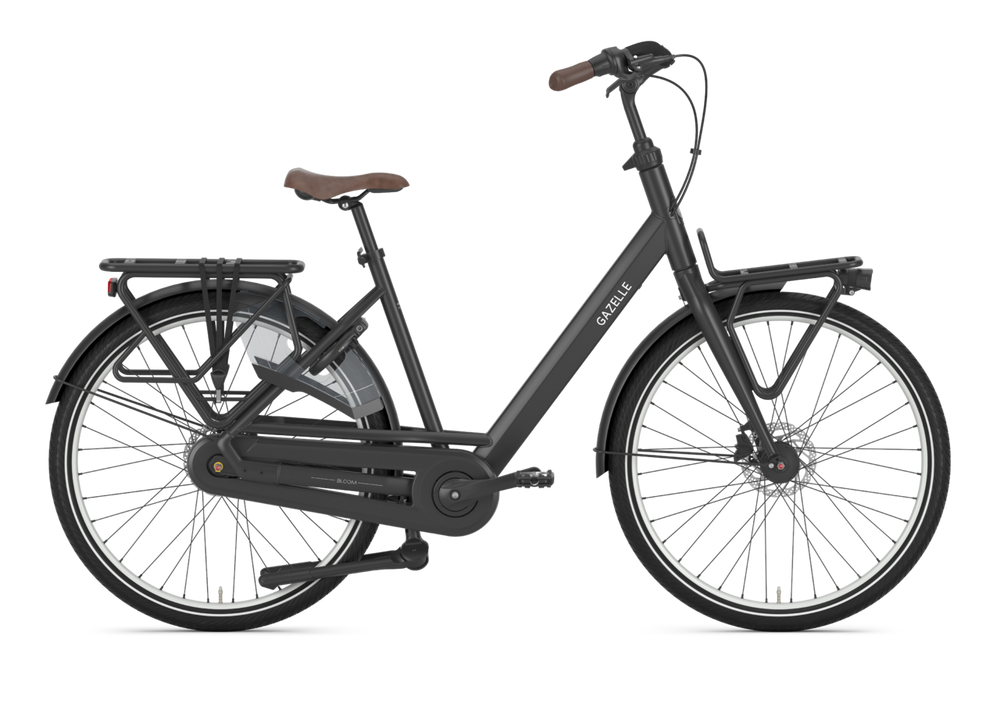 Billede af Gazelle Bloom Dame cykel i sort, der står på en vej omgivet af grønne træer, med fokus på cyklens elegante design og komfortable sæde.