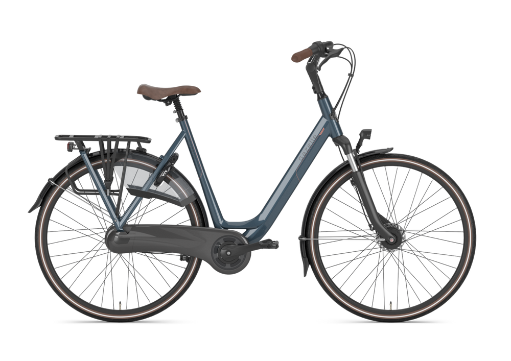 Gazelle Orange C7+ Dame cykel i farven Legion Blue, stående på en grusvej med grønne omgivelser.