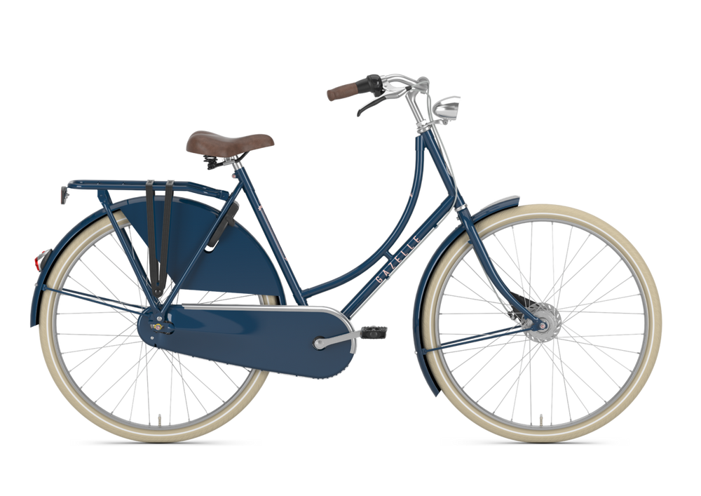 Billede af Gazelle Classic Dame cykel i farven Mallard Blue, der står på en vej med træer i baggrunden. Cyklen har et klassisk design med en komfortabel sadel og bredde dæk, ideel til bykørsel.