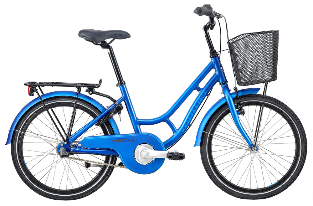Mat blå Winther 250 Granny Pige cykel med 20" hjul, designet til piger, står på en vej med træer i baggrunden.