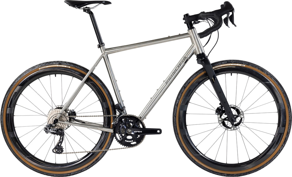 Principia Gravel 22Titan SRAM Force AXS 1x12sp Titanium cykel i et stilrent design, stående på en grusvej.