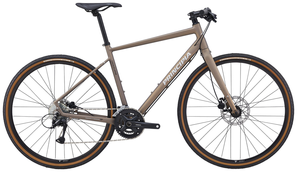 Principia Gravel H10 Unisex Kobber cykel på en grusvej med grønne træer i baggrunden.
