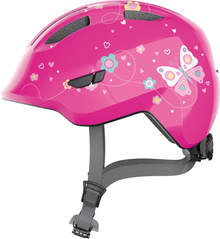 Abus Smiley 3.0 Pink Butterfly cykelhjelm med lyserøde sommerfugle på en lyserød baggrund.