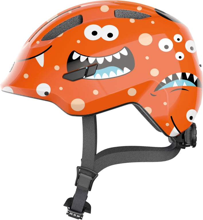 Cykelhjelm Abus Smiley 3.0 Orange Monster: En orange cykelhjelm med monsterdesign til børn, der giver sikkerhed og stil.